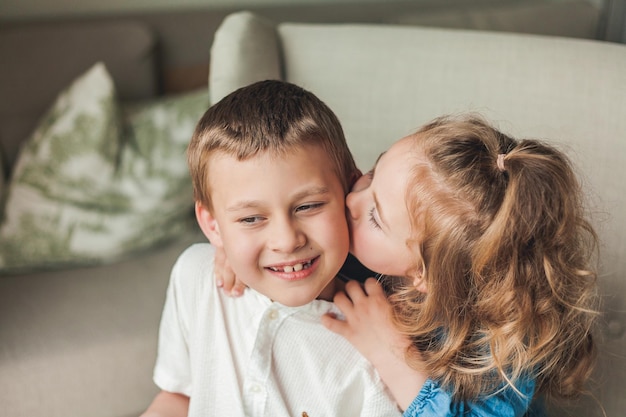 Portret van kleine gelukkige kinderen, broer en zus zitten in een gezellige fauteuil in een licht huis Familierelaties Thuisrust