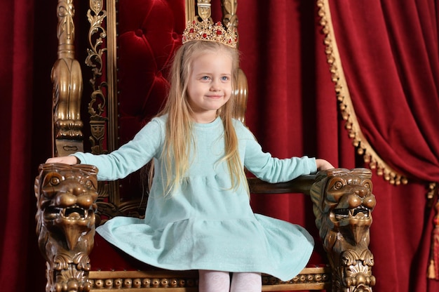 Portret van kleine meisjesprinses die zich voordeed op troon