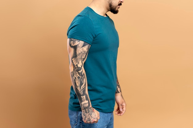 Portret van knappe aziatische man met stijlvolle tatoeage op armen in groen casual t-shirt geïsoleerd