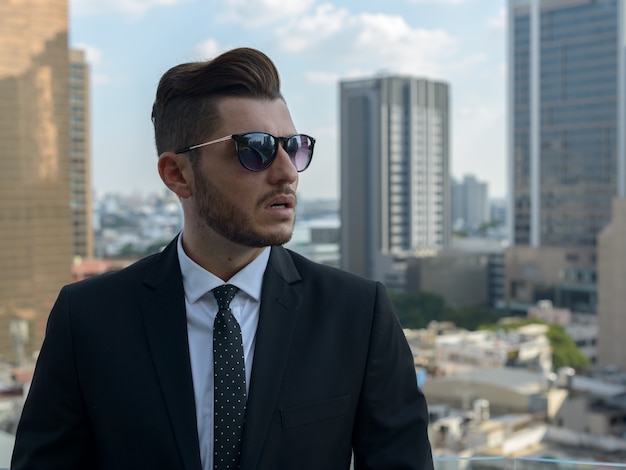 Portret van knappe bebaarde Spaanse zakenman tegen uitzicht over de stad