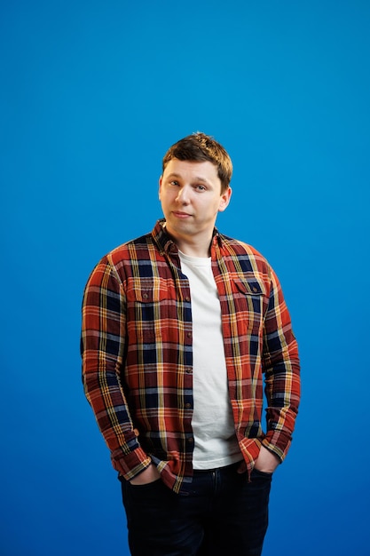 Portret van knappe europese man in shirt kijken camera staande op blauwe studio achtergrond