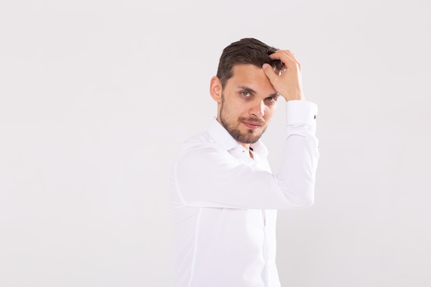 Portret van knappe gelukkige jonge man in casual shirt staande tegen een witte achtergrond