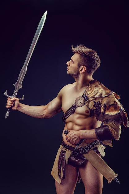 Portret van knappe gespierde gladiator met zwaard Geïsoleerde Studio shot