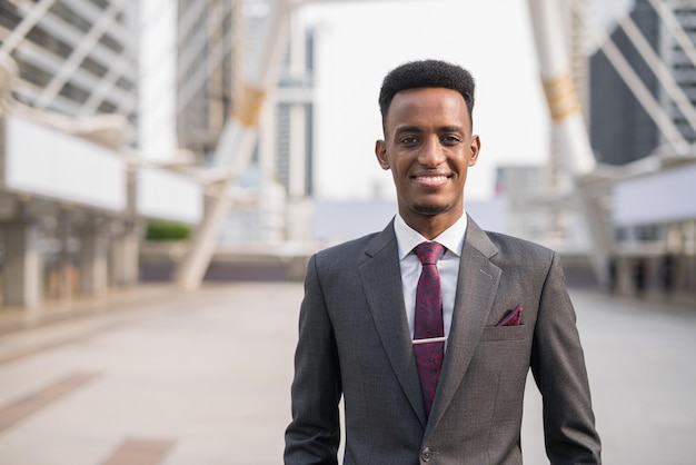 Portret van knappe jonge Afrikaanse zakenman buiten in de stad