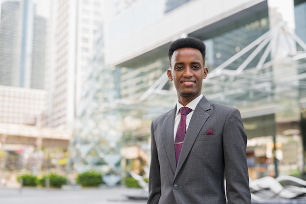 Portret van knappe jonge Afrikaanse zakenman buiten in de stad