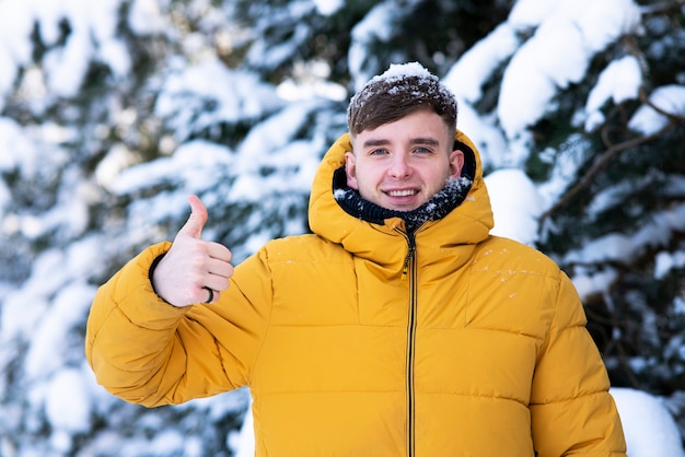 Portret van knappe jonge gelukkig man wandelen in warme gele donsjack buitenshuis