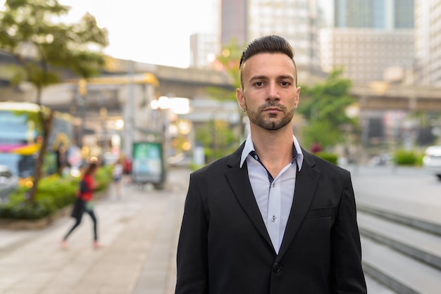 Portret van knappe jonge Italiaanse zakenman buiten in stad pak dragen