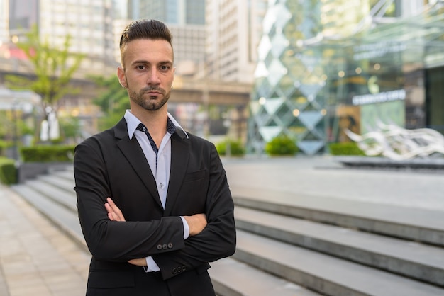 Portret van knappe jonge Italiaanse zakenman buiten in stad pak dragen
