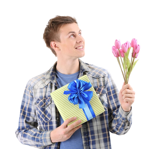 Portret van knappe jonge man met bloemen en cadeau, geïsoleerd op wit