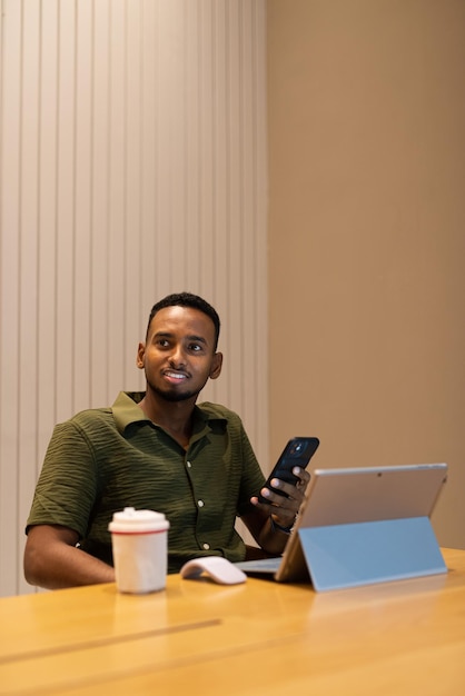 Portret van knappe jonge zwarte man met behulp van laptopcomputer in coffeeshop