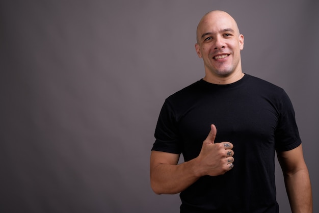 Portret van knappe kale man tegen een grijze achtergrond