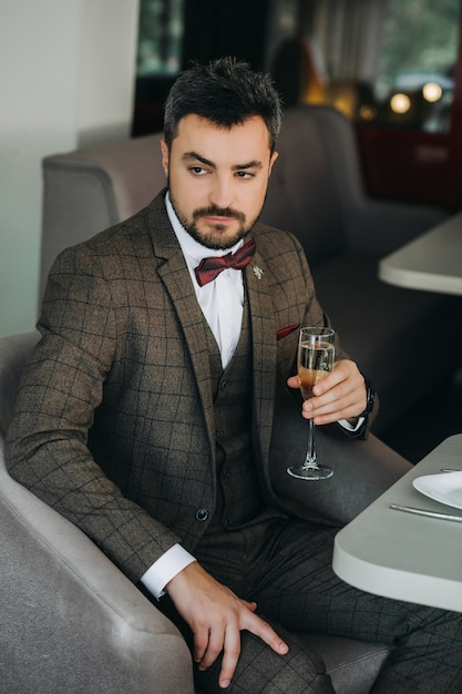 Portret van knappe man in pak houdt glas. een glas champagne in de hand van een brutale man