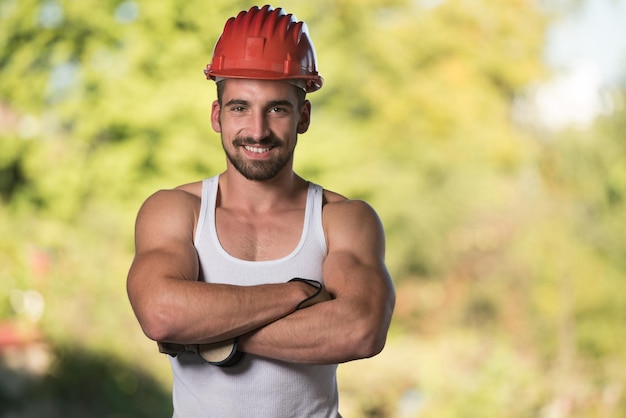 Portret van knappe mannelijke architect-ingenieur met rode helm