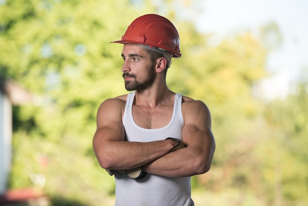 Portret van knappe mannelijke architect-ingenieur met rode helm