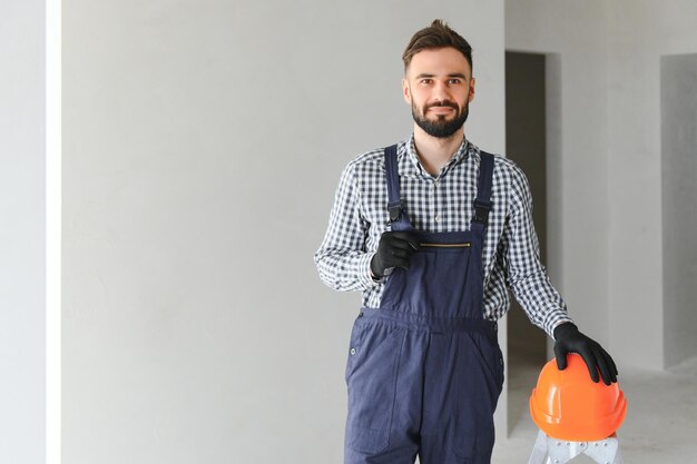 Portret van knappe monteur met stoppels in blauw overall shirt met zijn armen gekruist kijkend naar de camera