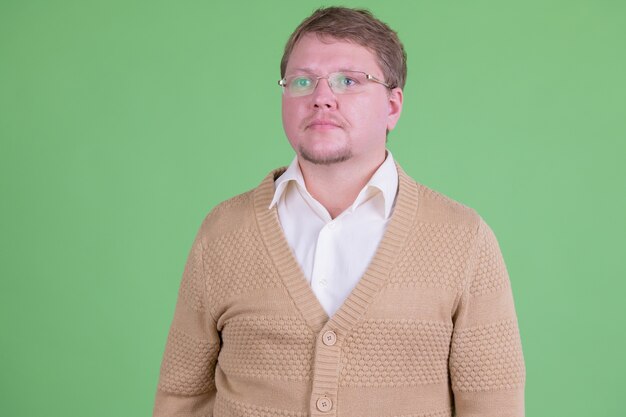 Portret van knappe overgewicht bebaarde man met bril tegen Chromakey of groene muur