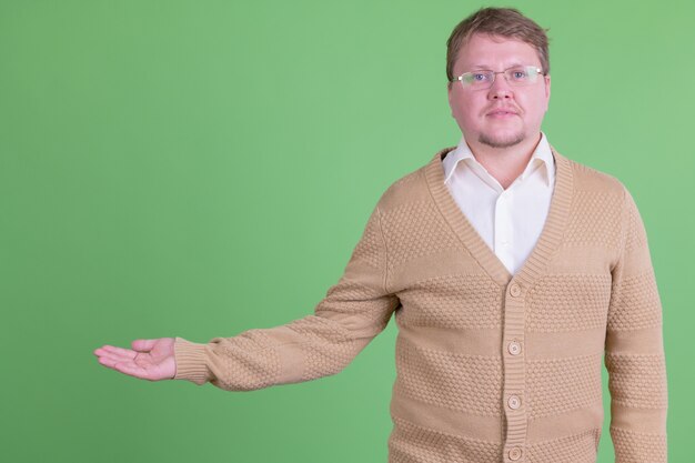 Portret van knappe overgewicht bebaarde man met bril tegen Chromakey of groene muur