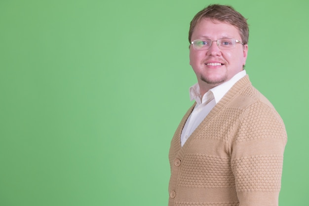 Portret van knappe overgewicht bebaarde man met bril tegen Chromakey of groene muur