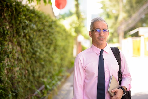 Portret van knappe Perzische zakenman met grijs haar in de stadsstraten in openlucht