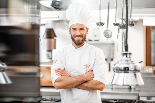 Portret van knappe positieve chef-kok in de keuken van het restaurant