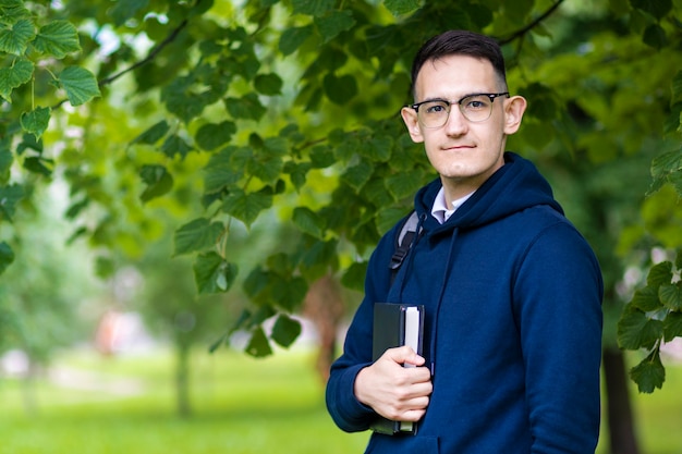 portret van knappe slimme student buiten in groen park