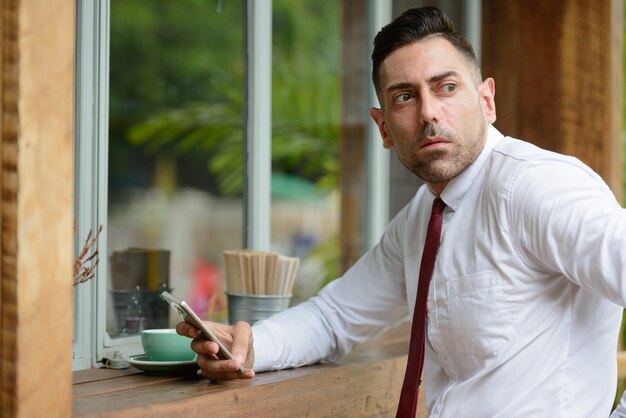 Portret van knappe zakenman met stoppelbaard ontspannen in de coffeeshop buitenshuis