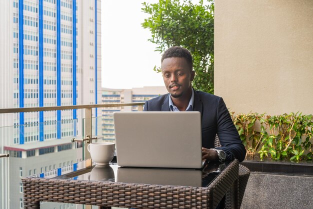 Portret van knappe zwarte afrikaanse zakenman die laptopcomputer met behulp van