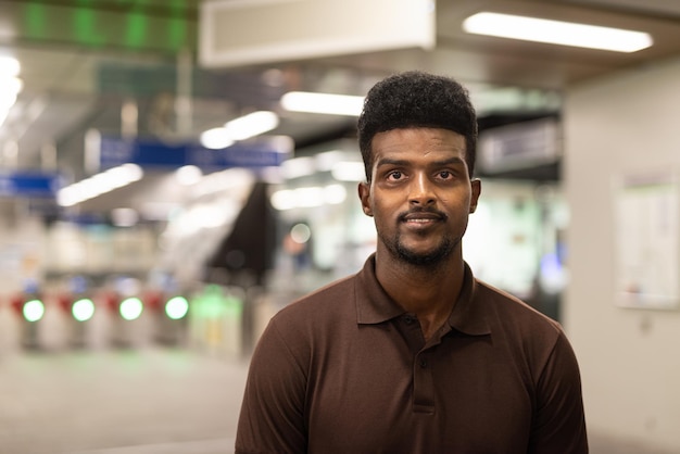 Portret van knappe zwarte man op treinstation tijdens de nacht