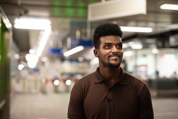 Portret van knappe zwarte man op treinstation tijdens de nacht