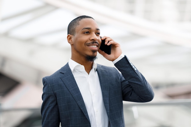 Portret van knappe zwarte zakenman praten op mobiele telefoon op de luchthaven