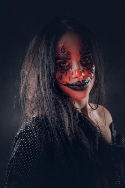 Portret van kwade Halloween-clown met rood licht op het gezicht bij donkere fotostudio.