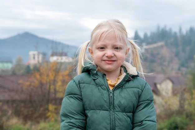 Foto portret van lachend blond meisje met twee staarten in de frisse lucht van het platteland vakantie in de herfst