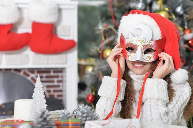 Portret van lachend meisje dat zich voorbereidt op Kerstmis, met een masker op