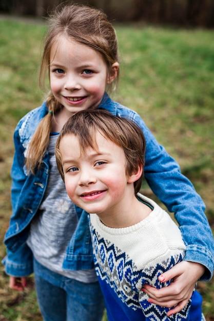 Portret van lachend meisje met broer staand op het veld