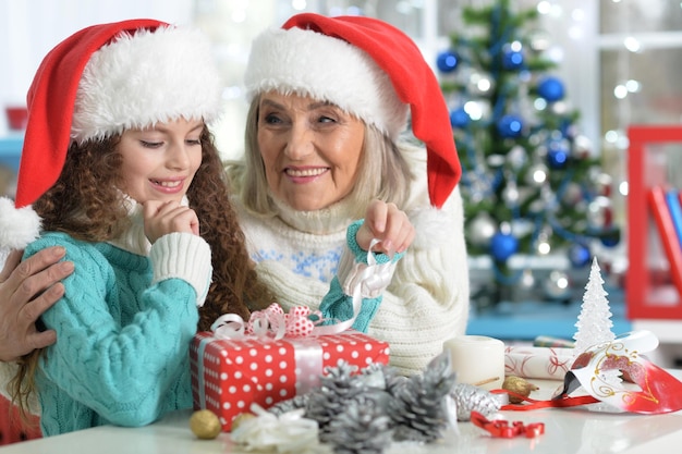 Portret van lachend meisje met grootmoeder die zich voorbereidt op Kerstmis