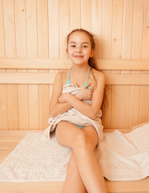 Portret van lachend meisje zittend op een bankje in de sauna