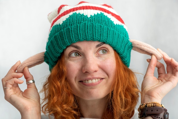 Portret van lachend roodharig meisje in een elfenhoed. Detailopname. Lichtgrijze achtergrond.