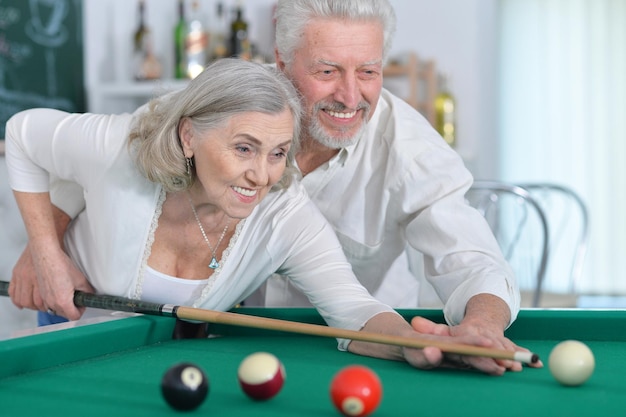 Portret van lachend senior koppel dat samen biljart speelt