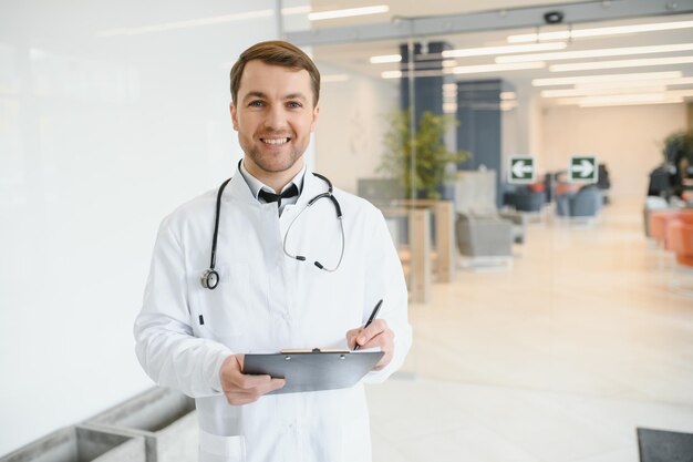 Portret van lachende arts in uniform staande in de hal van de geneeskundekliniek