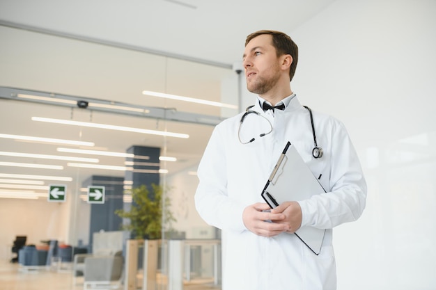 Portret van lachende arts in uniform staande in de hal van de geneeskundekliniek