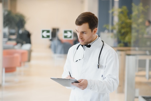 Portret van lachende arts in uniform staande in de hal van de geneeskundekliniek