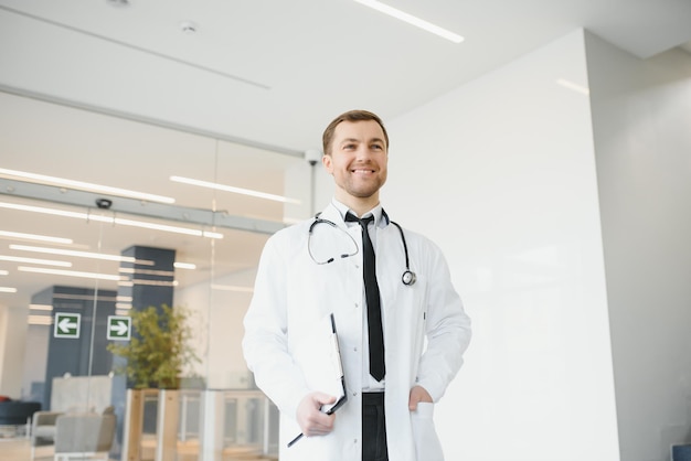 Portret van lachende arts in uniform staande in de hal van de geneeskundekliniek