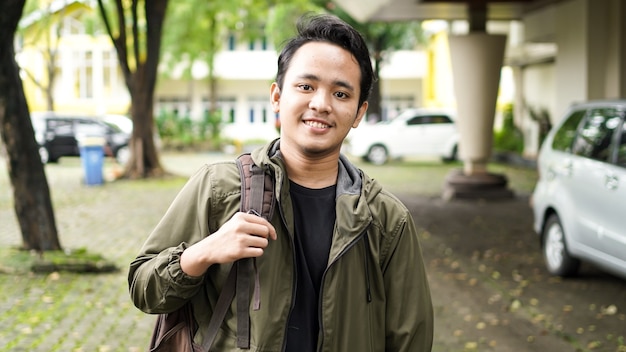 Portret van lachende Aziatische man met rugzak staan en staren naar de camera