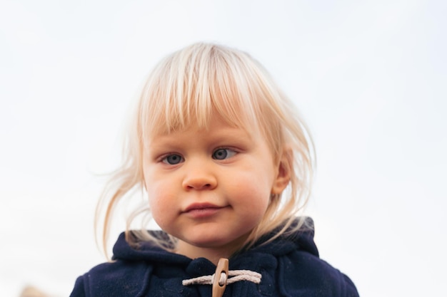 Portret van lachende babyjongen zittend op zand op het strand in de herfsttijd