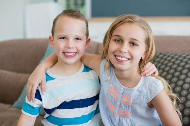 Portret van lachende broer en zus omarmen op de Bank in de huiskamer