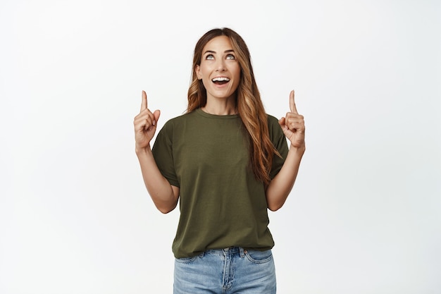 Portret van lachende brunette vrouw, omhoog kijkend en wijzend