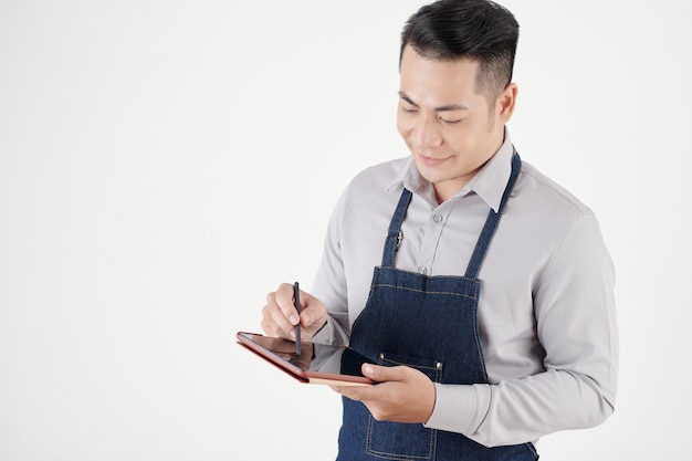 Portret van lachende café-eigenaar die online bestellingen op tabletcomputer controleert