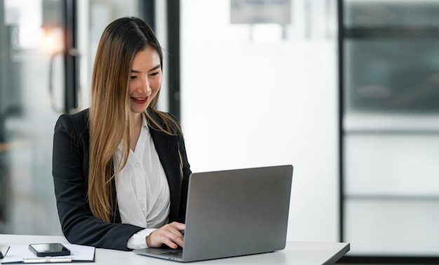 Portret van lachende dame executive bezig met laptop op werkplek in modern kantoor