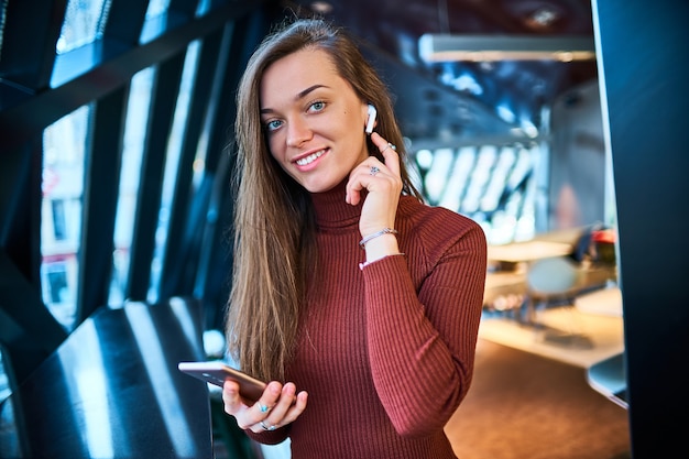 Portret van lachende gelukkig jonge blanke brunette vrouw met witte draadloze koptelefoon