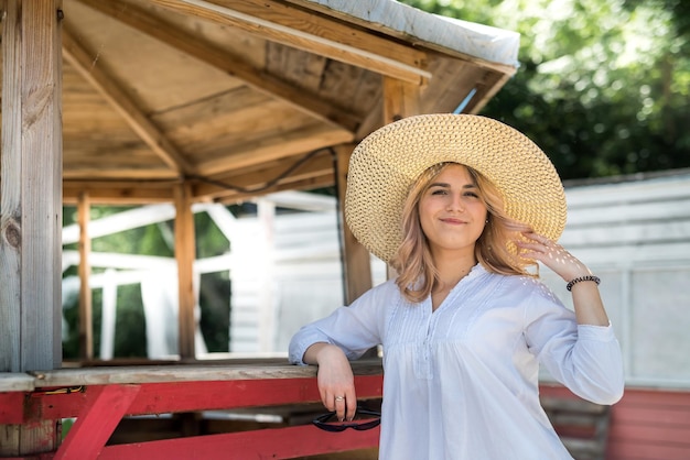 Portret van lachende jeugdige vrouw die geniet van vakantietijd, in de buurt van zandstrand in houten prieel.